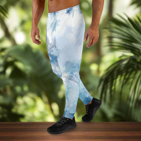 Person wearing blue tie-dye pants walking on a wooden platform with a green, leafy background